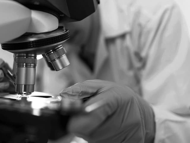 Picture depicting a microscope and a person using it in the background